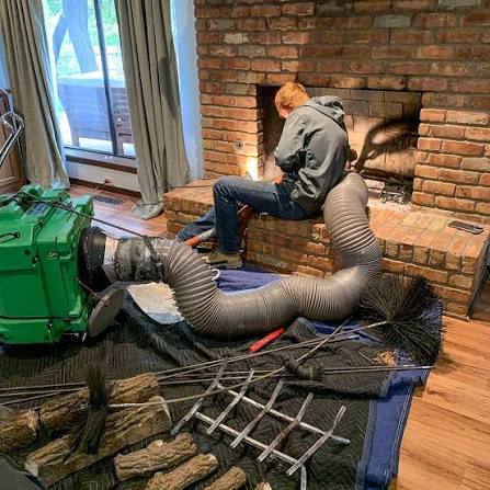 Rods, brushes and a green vacuum unit set up in front of a raised brick hearth
